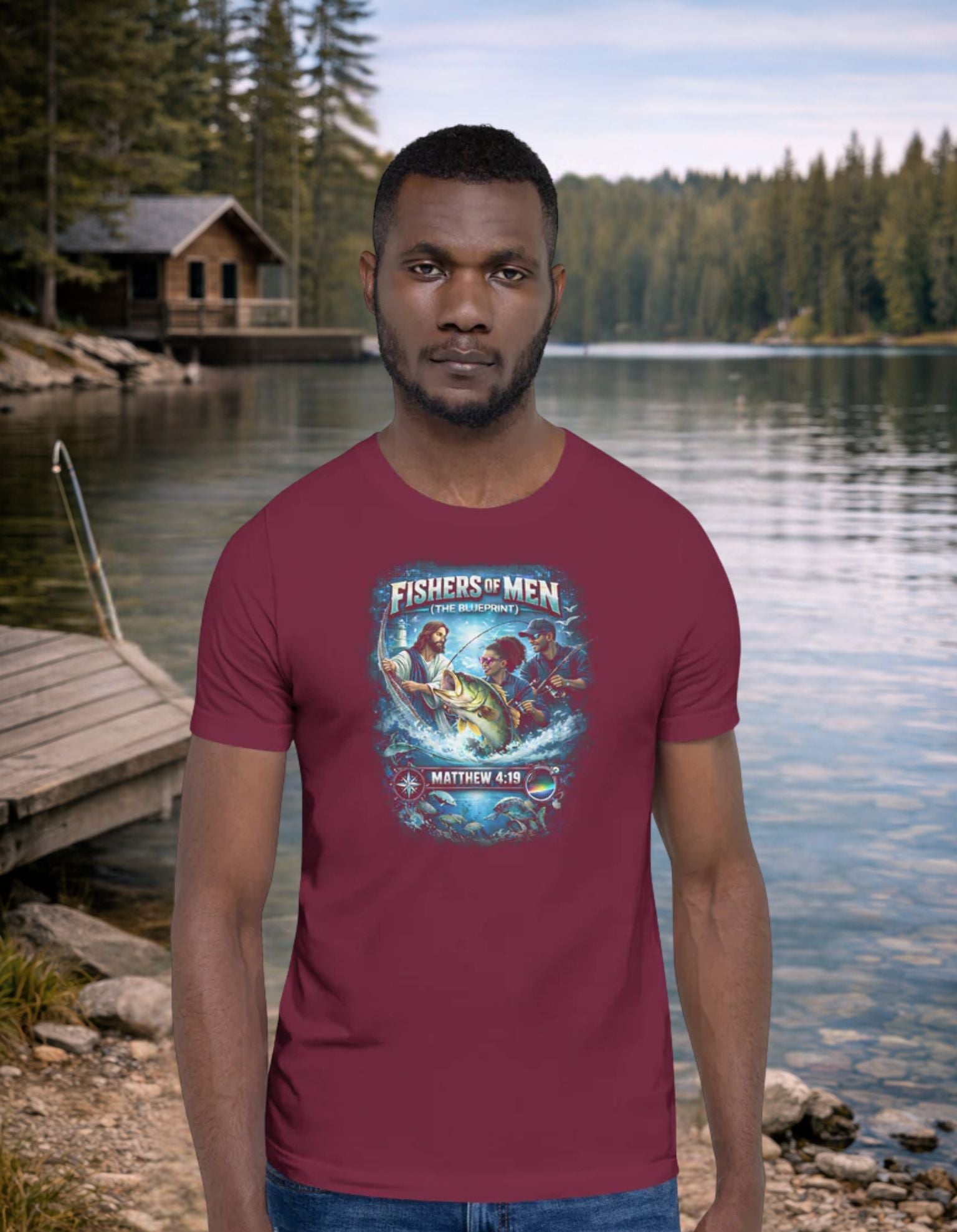 Man wearing a Christian Fishing red t-shirt with a graphic design standing by a lake with a cabin in the background.