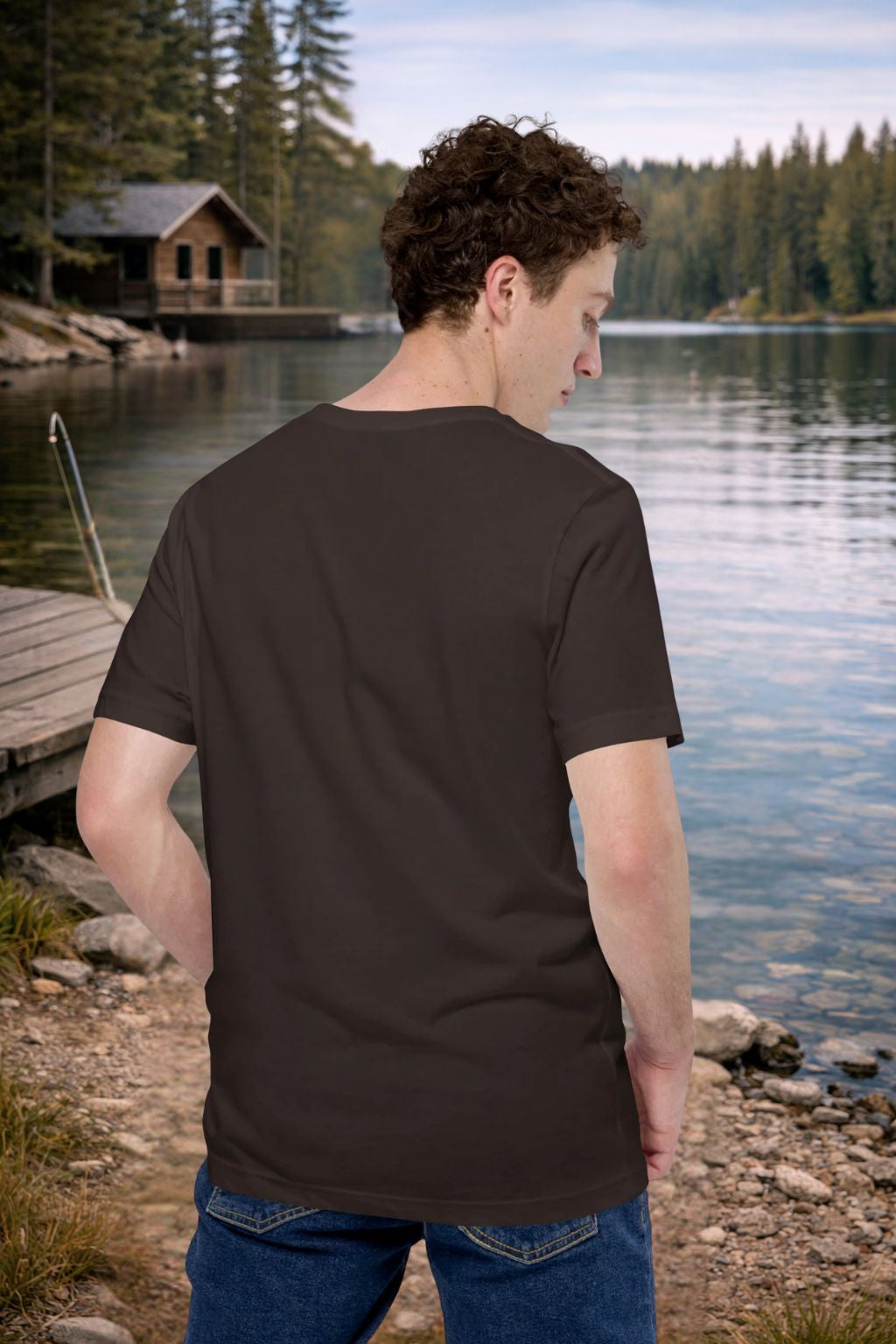 Man wearing a Back Angler t-shirt by a lake with a cabin in the background