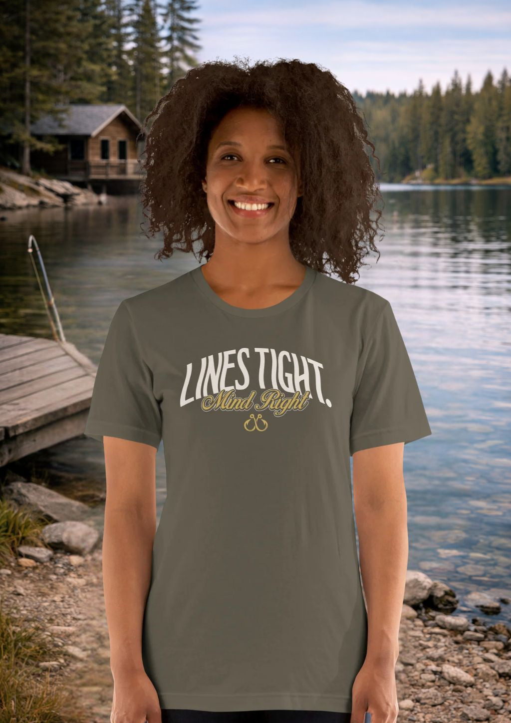 Person wearing a t-shirt with 'LINES TIGHT Mind Right' text by a lake with a cabin in the background